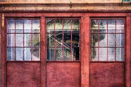 Weathered glass pane with faint reflections of towering shipyard machinery at Mare Island, ghostly and atmospheric